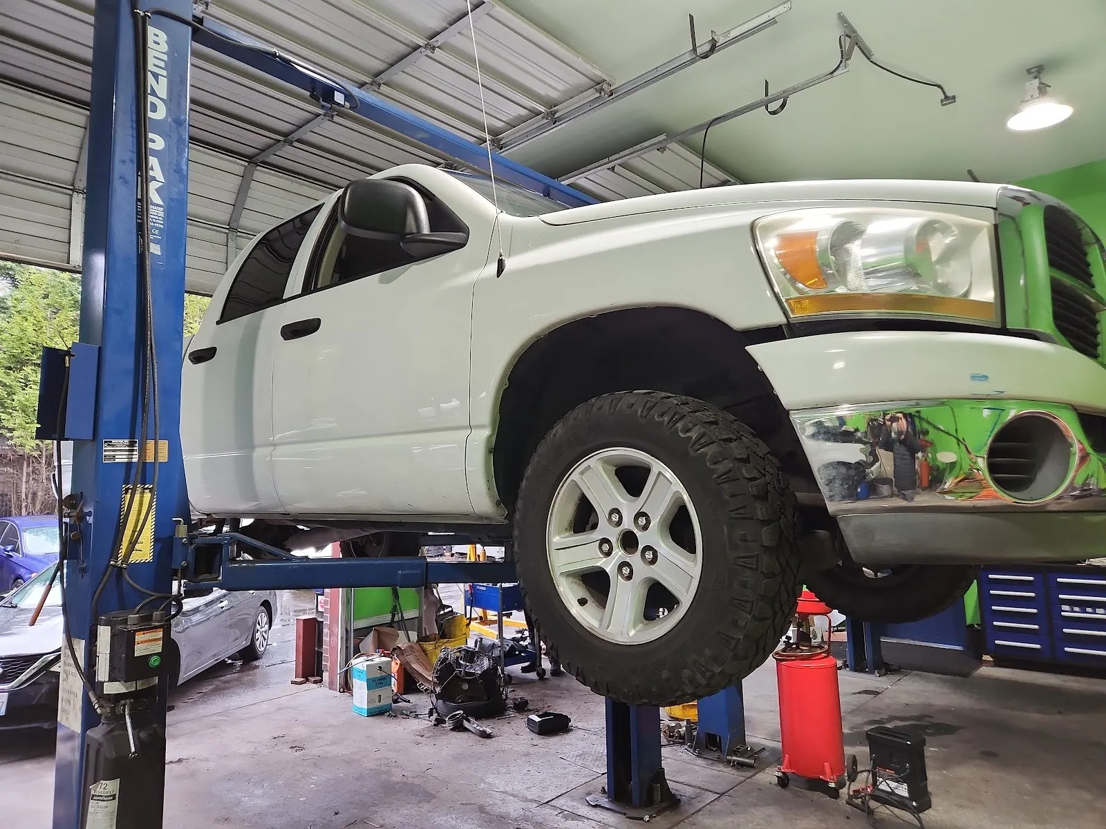 A white Dodge Ram up on the blue two-post lift inside the shop